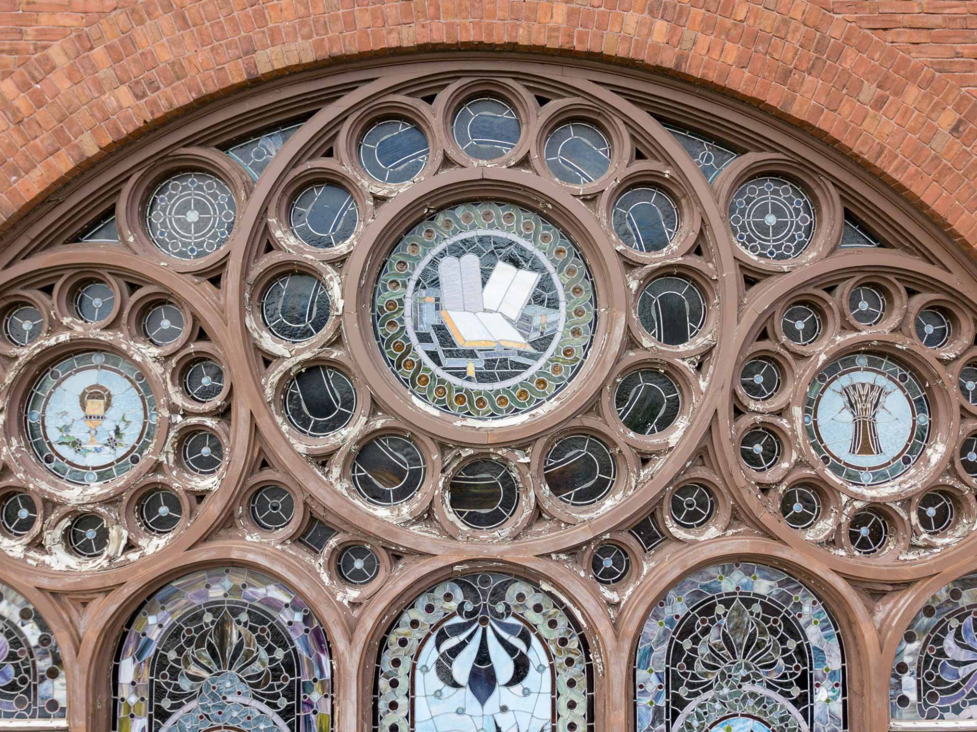 Stained glass window with faded, worn wooden framing